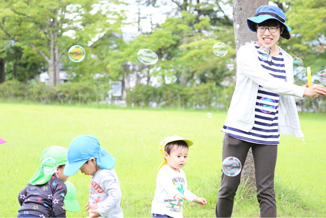 屋外で子どもたちとシャボン玉遊びをする様子
